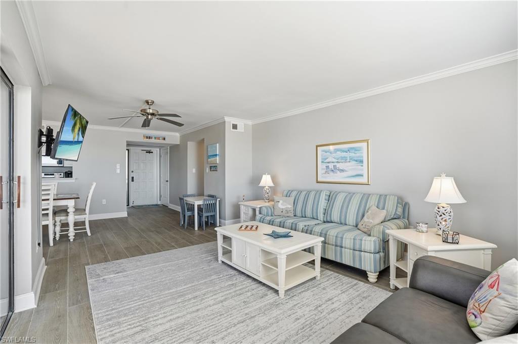 Living area with light wood-style flooring, ornamental molding, and a ceiling fan