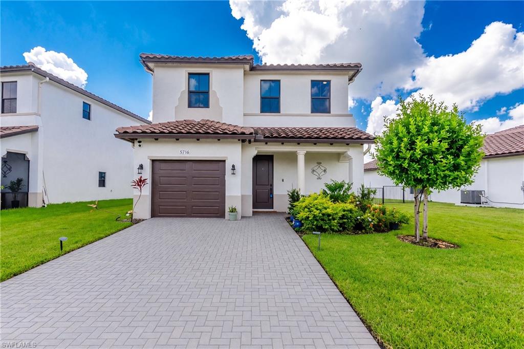 Two-story stucco exterior with a tile roof and a paver driveway