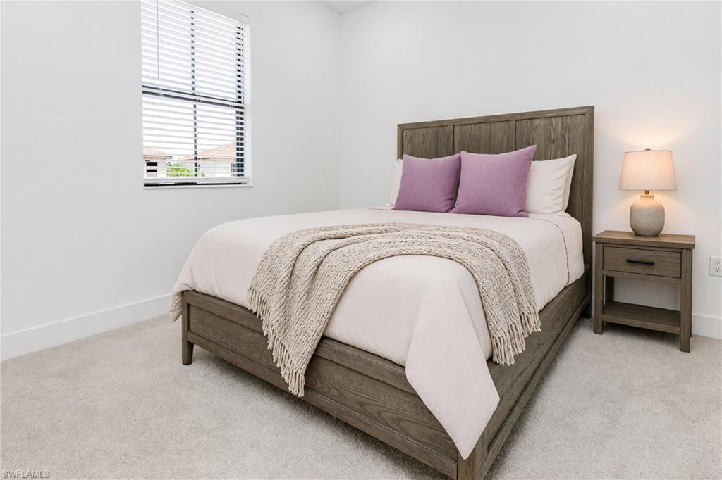 White walls, window with blinds, light-colored carpeting, wood-finish bed frame, wood-finish nightstand with drawer