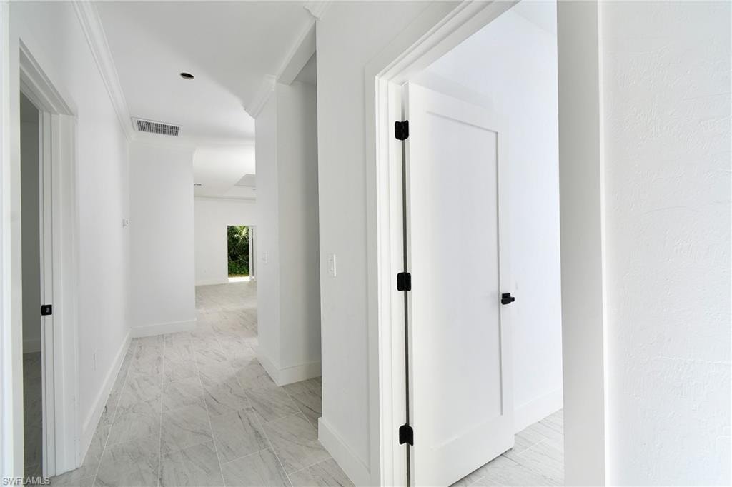 Hallway featuring light-toned tile flooring, white walls, and white trim
