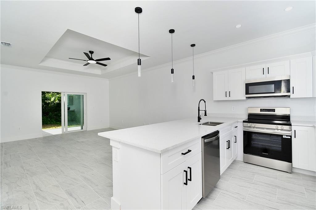 White shaker cabinetry, stainless steel appliances, and a kitchen island with pendant lighting