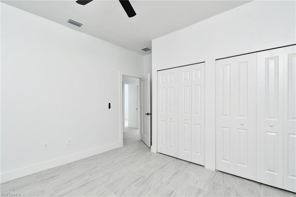 White panel bi-fold doors, tile flooring, recessed ceiling, modern ceiling fan, and white baseboards