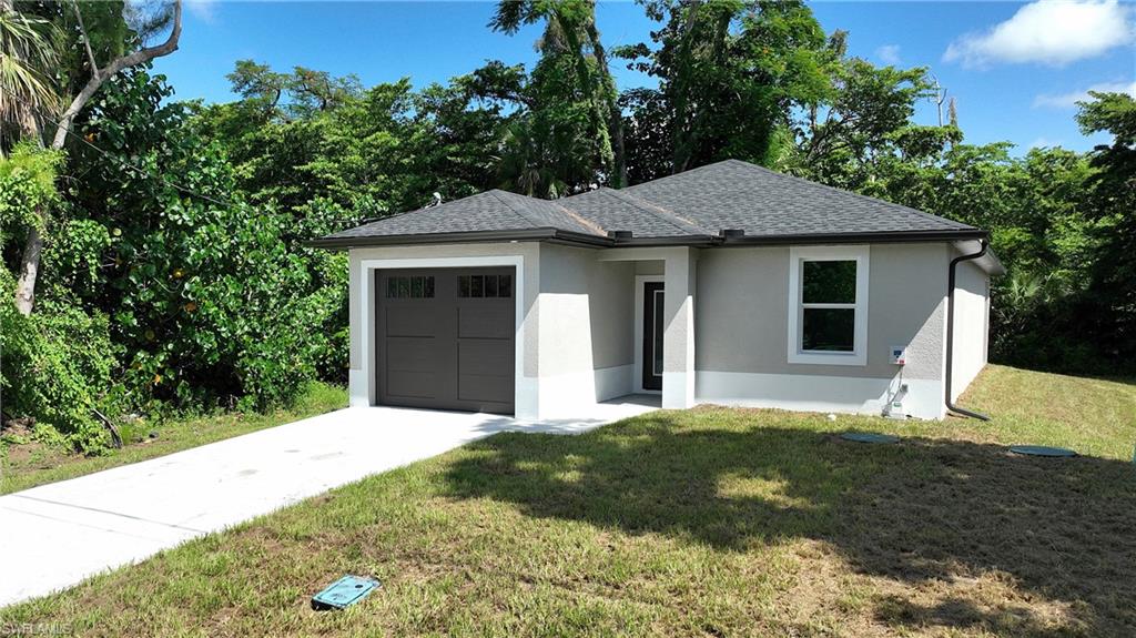 Contemporary stucco exterior featuring an attached garage with a dark wood-finish door, a paved driveway, and a shingled roof
