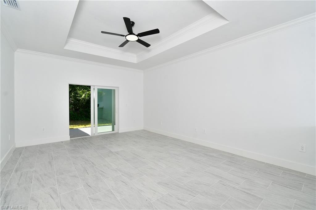 Recessed tray ceiling with crown molding and a ceiling fan, white walls, and large format tile flooring