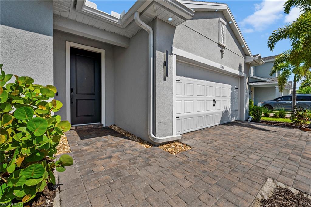 Textured stucco exterior with a paneled garage door and a dark paneled entry door
