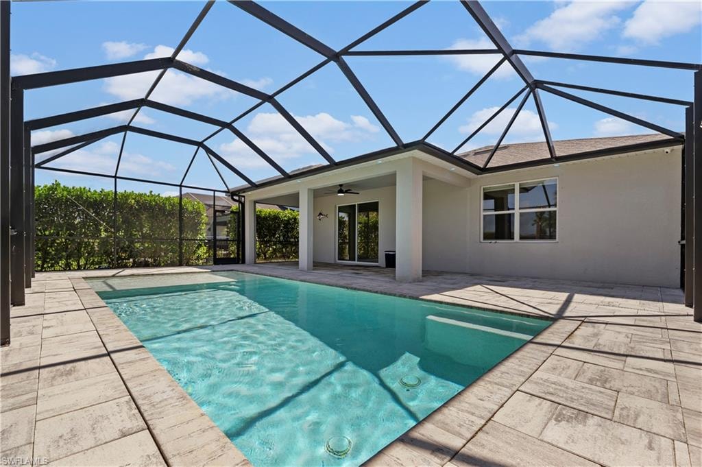 Screened outdoor living area featuring a rectangular pool, integrated spa, and expansive paver patio