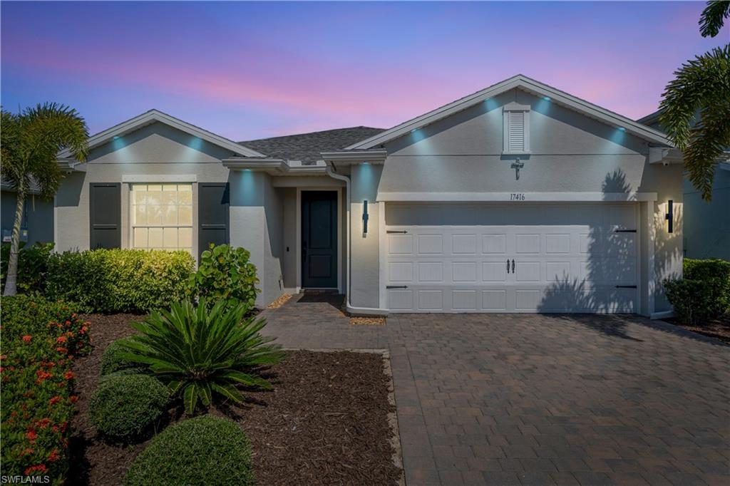 Smooth stucco exterior with a covered entry, dark front door, and a two-car garage