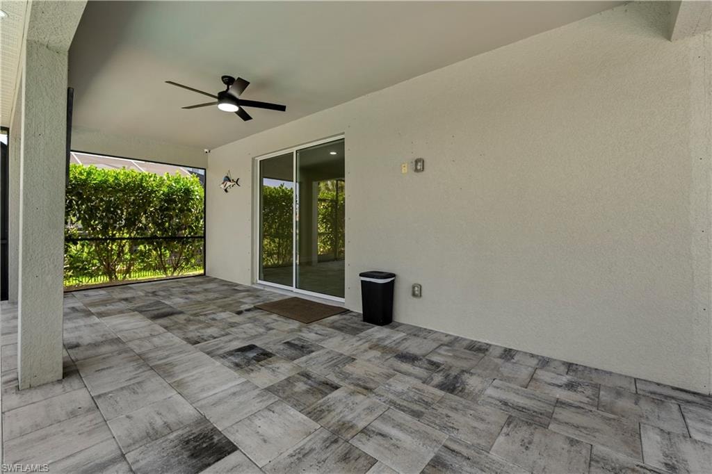 Screened patio with large format tile flooring, black ceiling fan, and sliding glass door