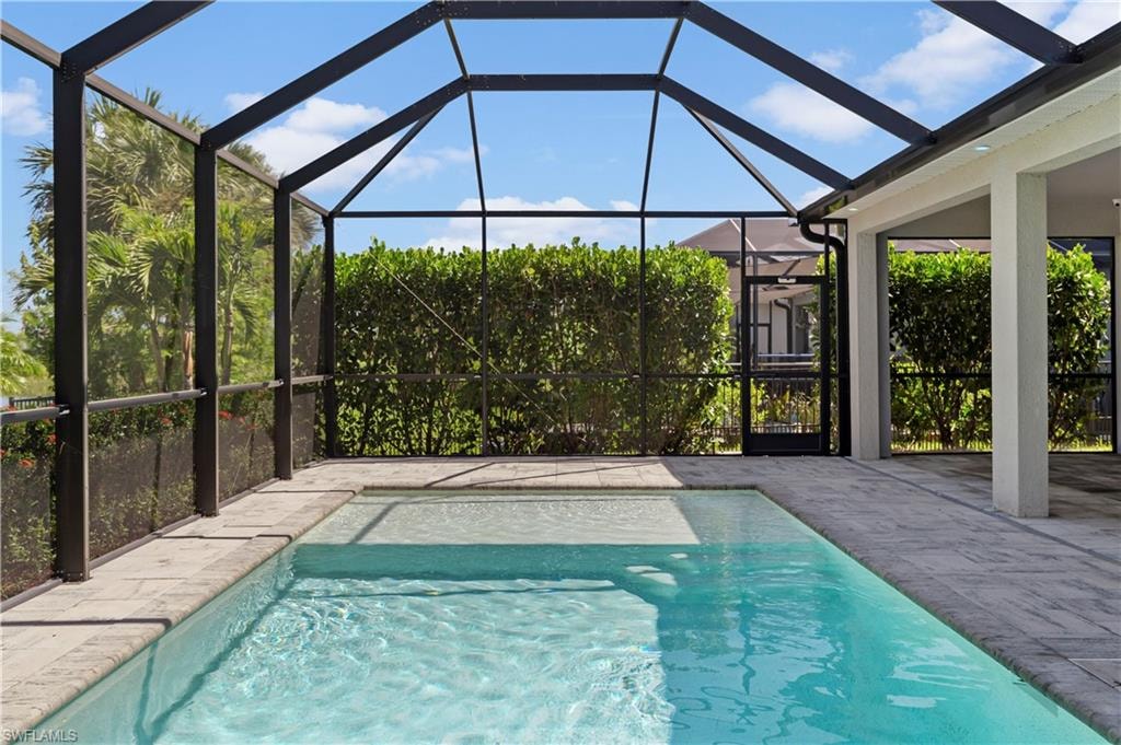 Screened outdoor living area featuring a swimming pool, integrated spa, and paver decking