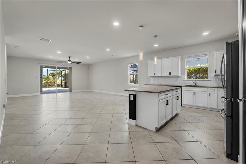 Open-concept living space featuring neutral tile flooring, recessed lighting, and a ceiling fan