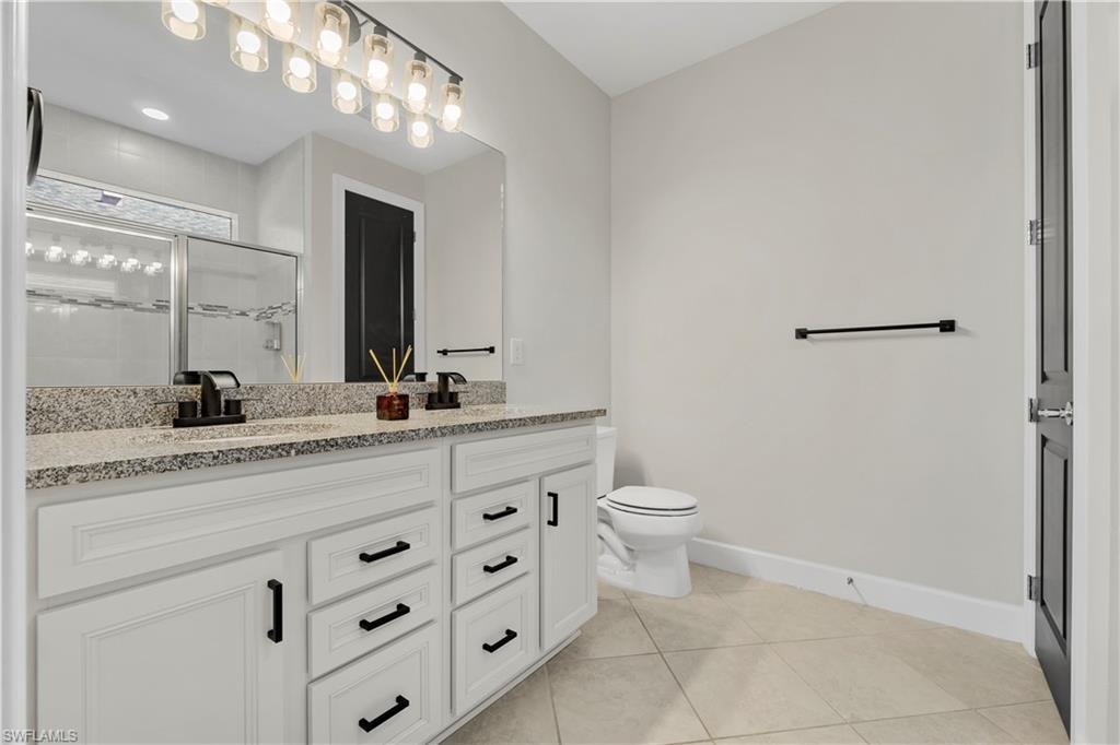 Double vanity with stone countertop, matte black fixtures, and integrated sinks