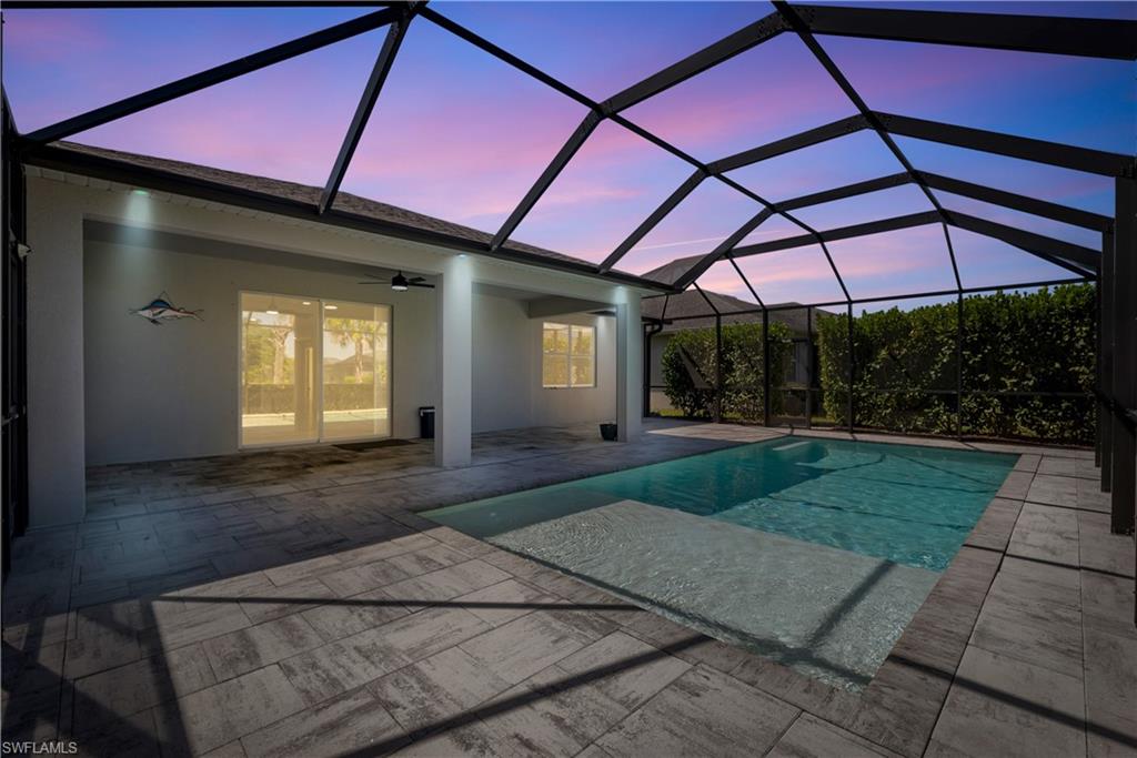 Screened-in outdoor living space with a swimming pool, integrated spa, and expansive paver decking