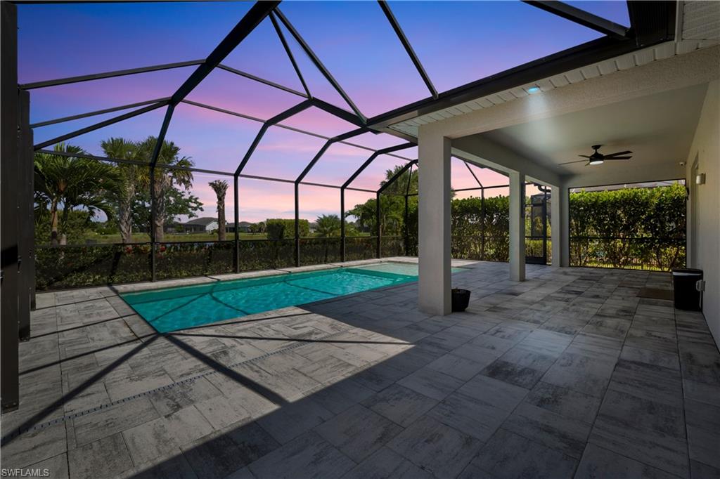 Screened lanai with a rectangular pool, gray tile flooring, and a ceiling fan