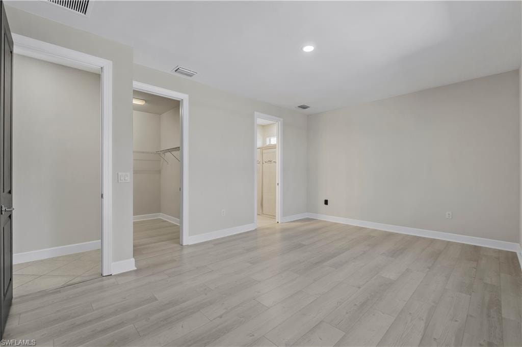 Light wood-finish flooring, recessed lighting, and a walk-in closet with wire shelving