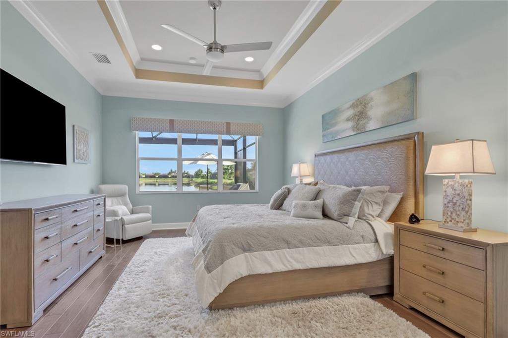 Tray ceiling with recessed lighting and a ceiling fan, wood-finish flooring, and a large window
