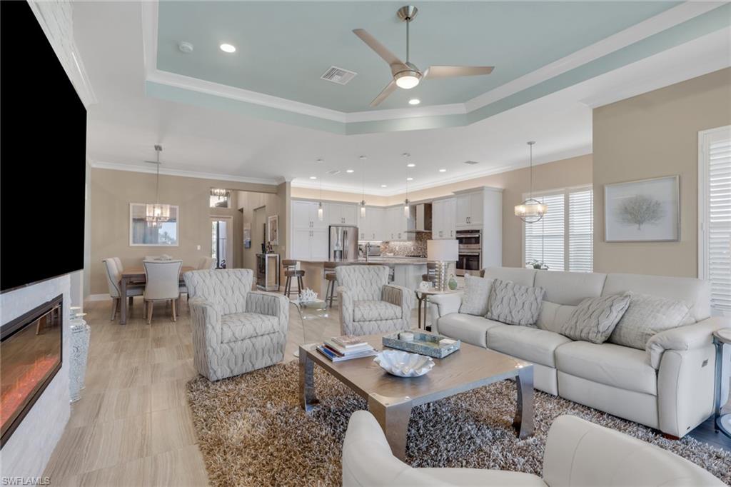 Open-concept living area featuring a tray ceiling with a ceiling fan, recessed lighting, and wood-finish flooring