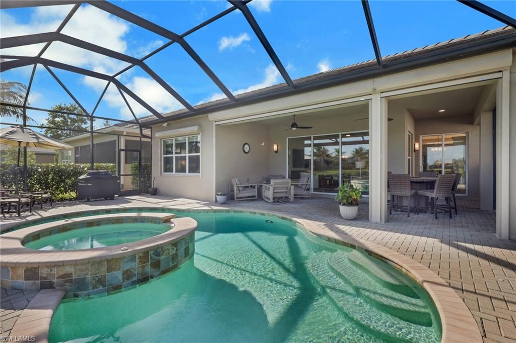 Screened lanai featuring a swimming pool, integrated spa with tile surround, and paver decking