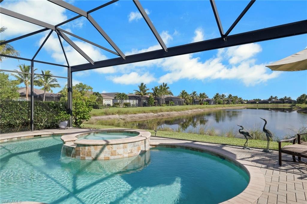 Screened lanai featuring a swimming pool, integrated spa with stone tile surround, and a paver patio