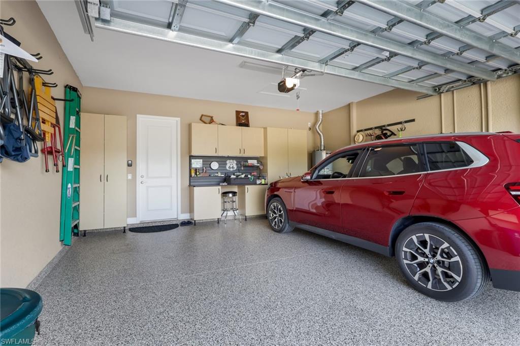Garage with speckled epoxy flooring, built-in cabinetry, and a service door