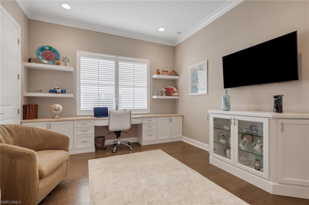 Built-in desk with overhead shelving, custom cabinetry with display cases, wood-finish flooring, recessed lighting, and crown molding