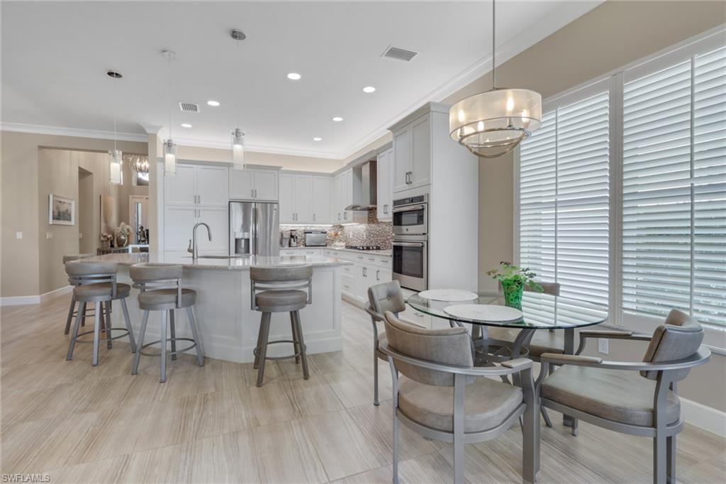 Spacious kitchen with a large island, stainless steel appliances, and white cabinetry