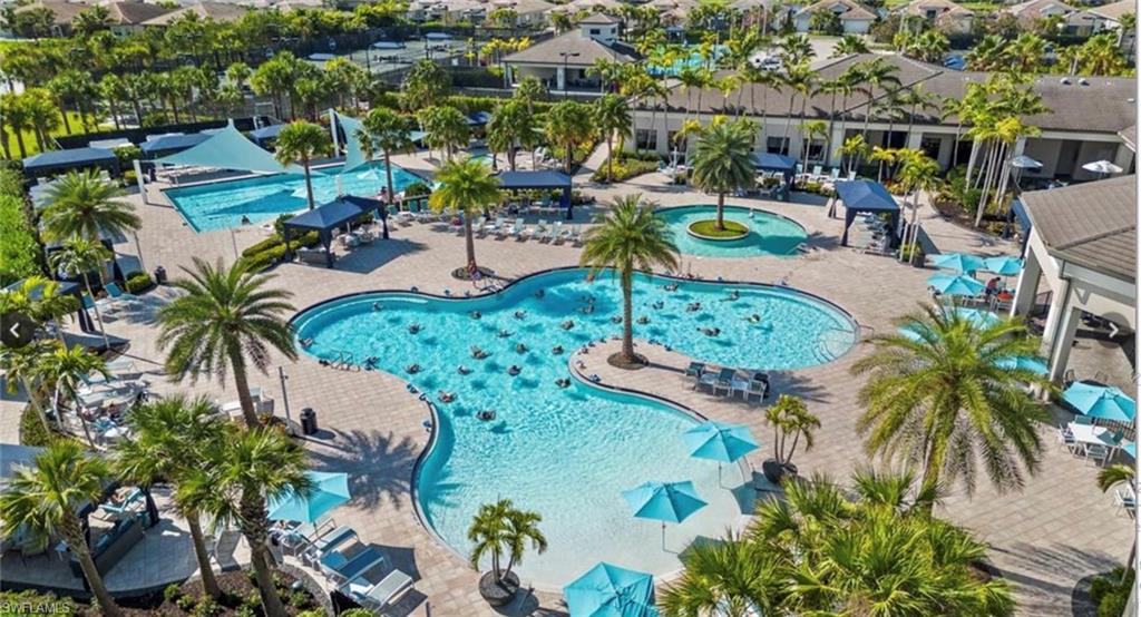 Expansive resort-style pool complex featuring multiple swimming areas, a large sundeck with lounge seating, multiple shaded cabanas, and established palm trees