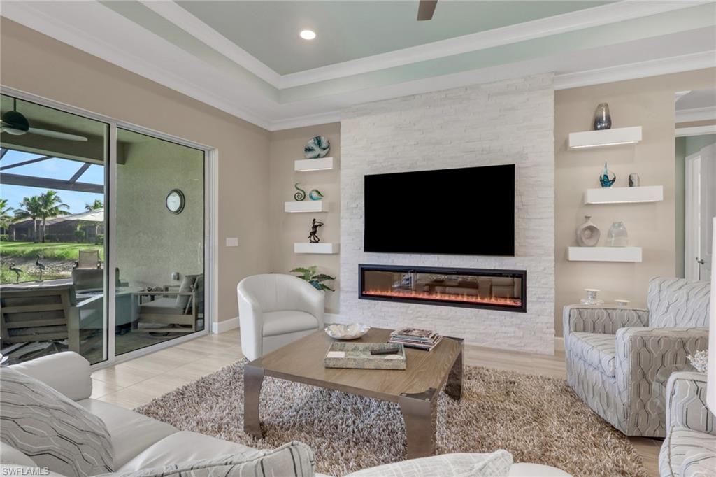 Tray ceiling with recessed lighting, stone-finish accent wall with an integrated linear fireplace, and floor-to-ceiling sliding glass doors