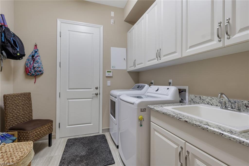 Laundry area featuring white cabinetry, integrated sink, and light-toned flooring