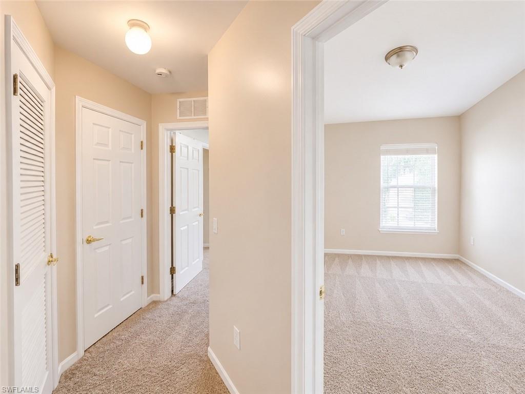 Neutral tone wall paint, textured carpeting, white six-panel interior doors, white louvered door, and overhead flush-mount lighting