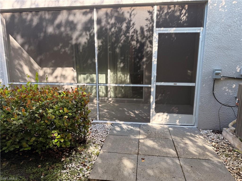 Screened patio enclosure with a concrete tile walkway and surrounding gravel