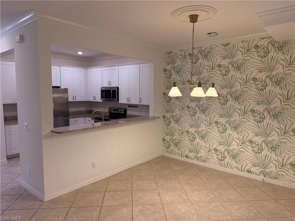 Kitchen pass-through with granite countertops, stainless steel appliances, white cabinetry, and tile flooring