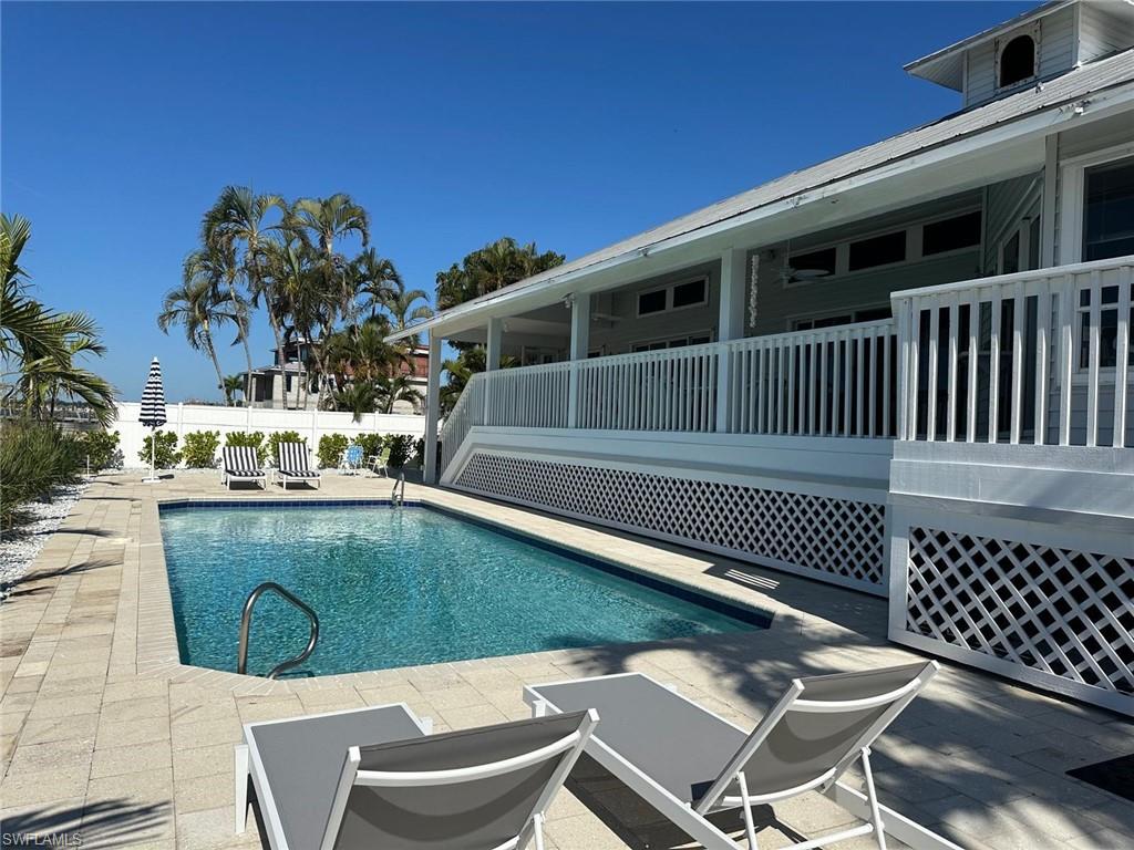 Expansive outdoor area featuring a rectangular swimming pool, paver deck, and surrounding low-maintenance landscaping