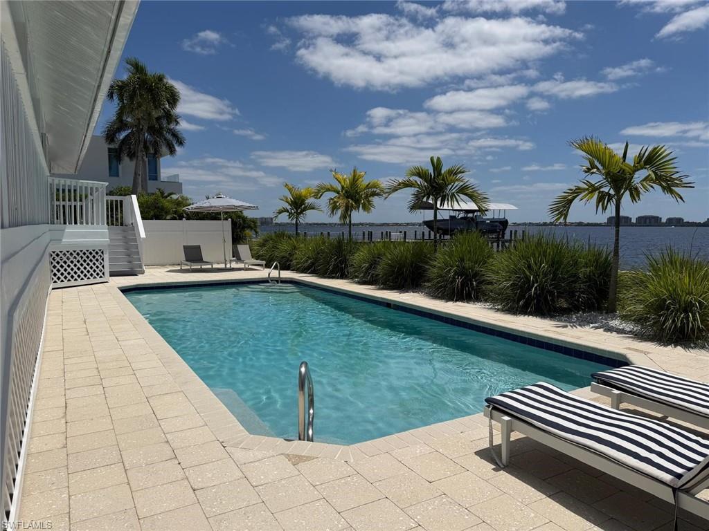 Rectangular swimming pool featuring a tiled waterline, integrated steps, and a stainless steel handrail