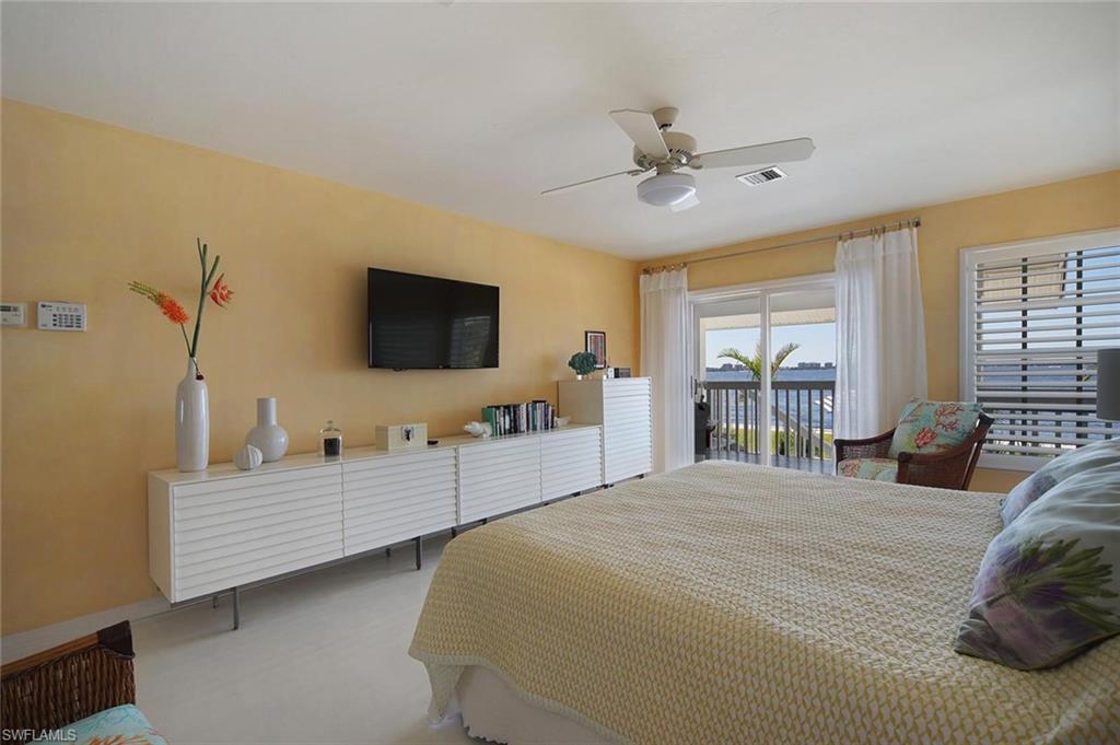 Bedroom featuring a sliding glass door leading to a balcony, white plantation shutters, a ceiling fan with integrated lighting, and light-colored flooring
