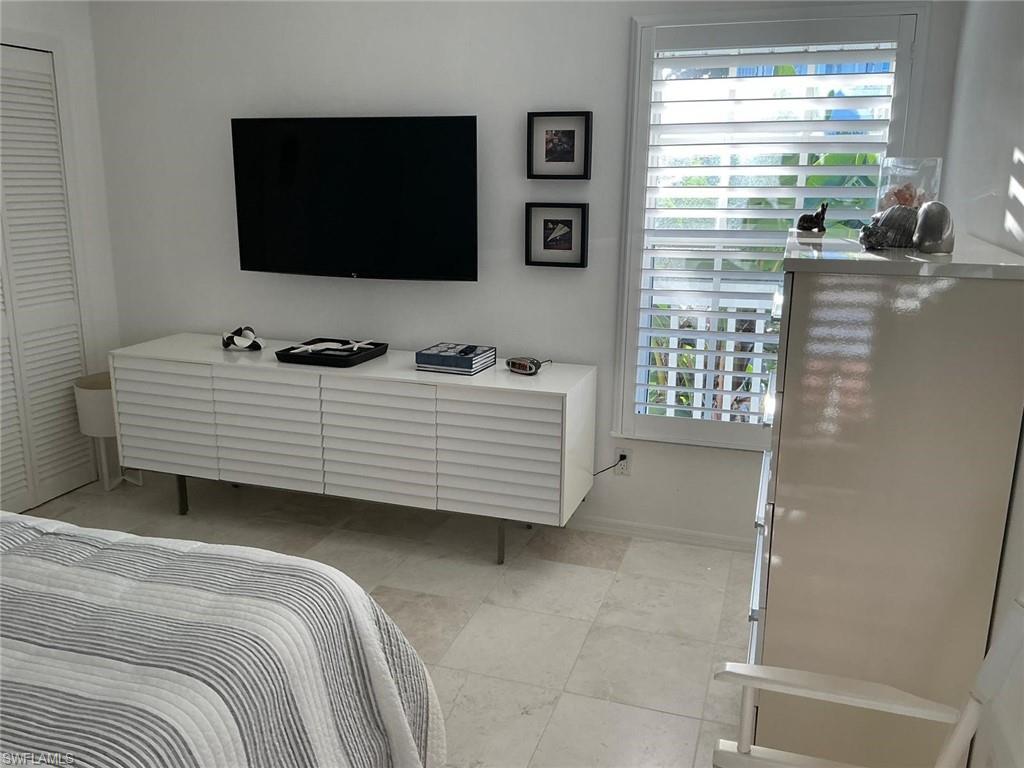 Wall-mounted media console with slatted fronts, plantation shutters, and light-toned tile flooring