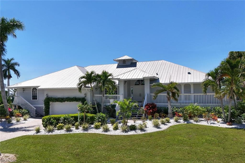 Elevated residence featuring a metal roof, white siding, and an inviting porch with railing