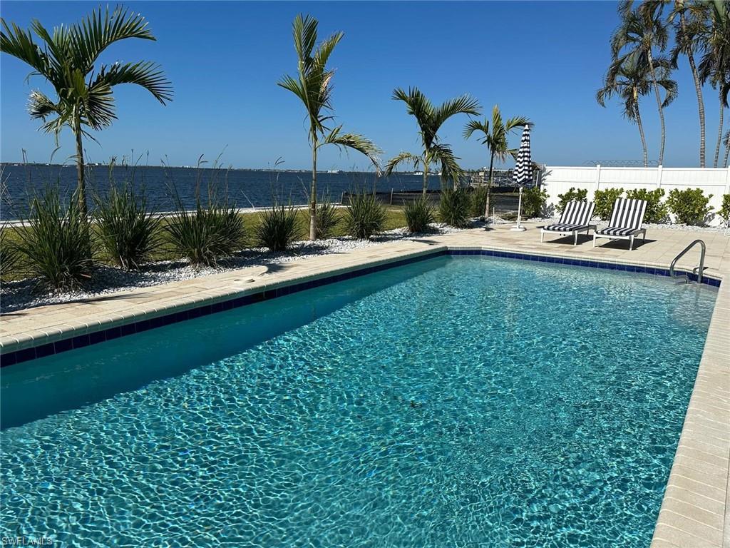Rectangular swimming pool featuring a tiled waterline, light-colored coping, and surrounding paver decking