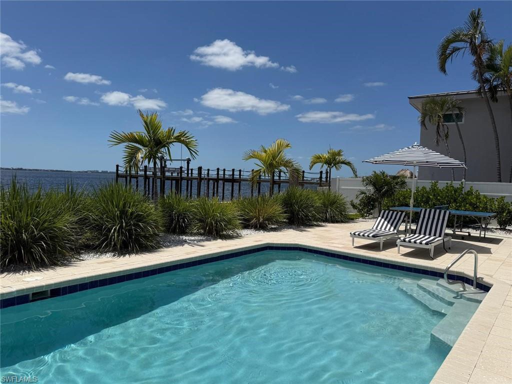 In-ground swimming pool with integrated steps, surrounded by light-toned pavers and lush landscaping