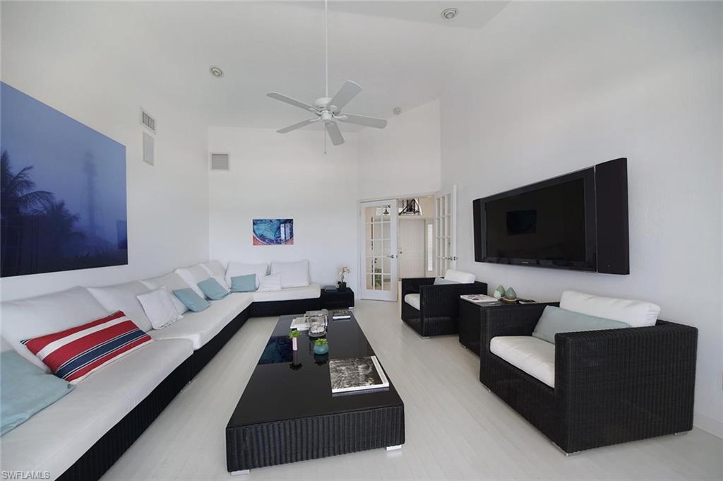 Spacious living area featuring high vaulted ceilings, light-tone wood-finish flooring, and crisp white walls