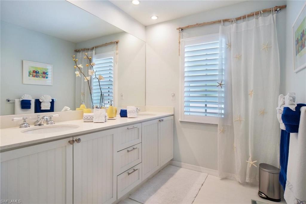 Bathroom featuring a dual vanity with white beadboard cabinetry, integrated sinks, and polished chrome fixtures