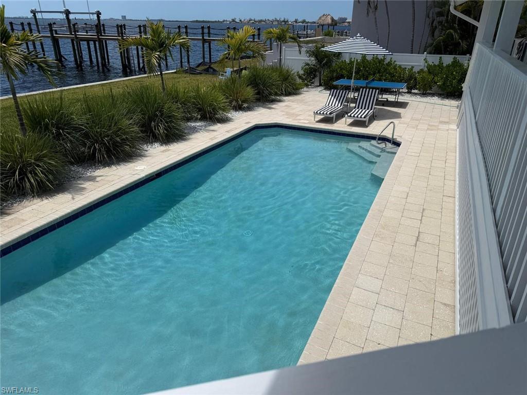 Exterior swimming pool with integrated steps, surrounded by light-colored paver decking