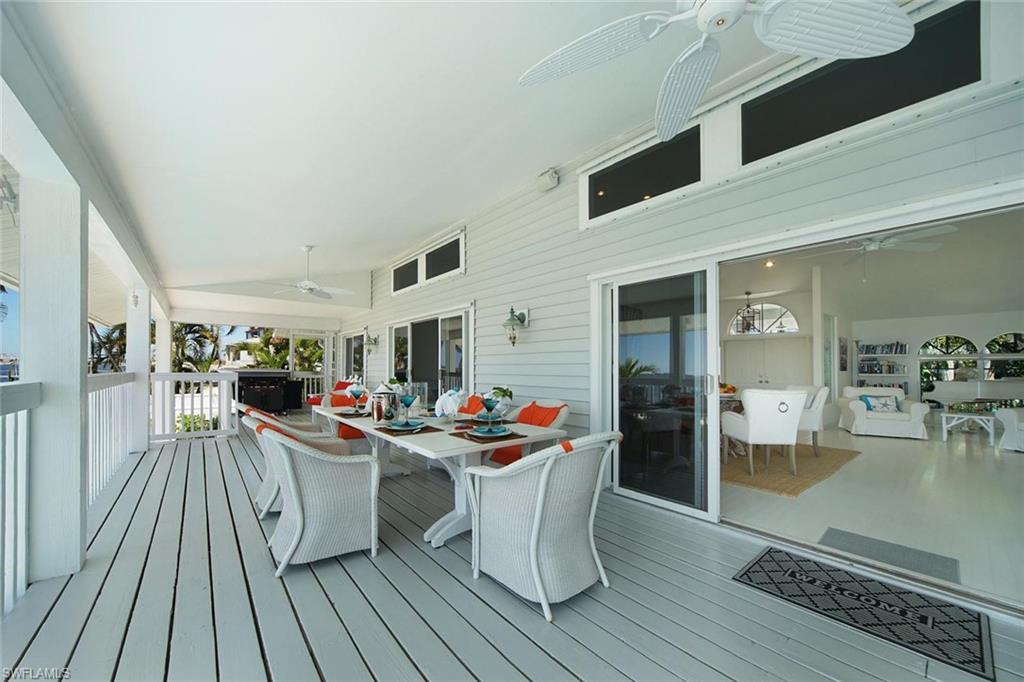 Expansive covered porch featuring light-colored decking, white railings, and multiple ceiling fans