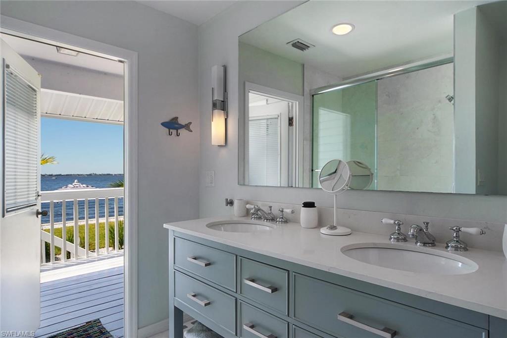 Dual vanity with integrated sinks and chrome fixtures, illuminated by contemporary wall sconces