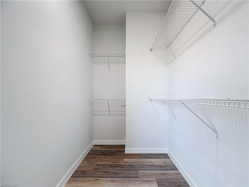 Walk in closet with dark wood-style flooring