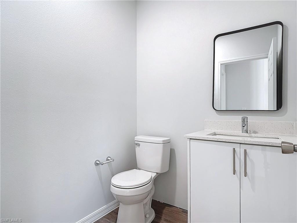 Half bathroom featuring vanity and dark wood-style flooring
