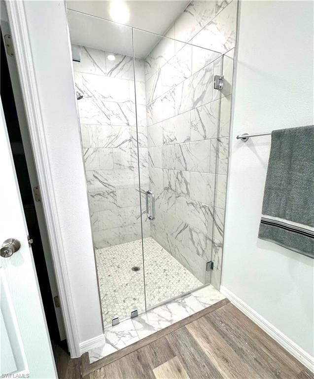 Full bathroom with a marble finish shower and wood finished floors