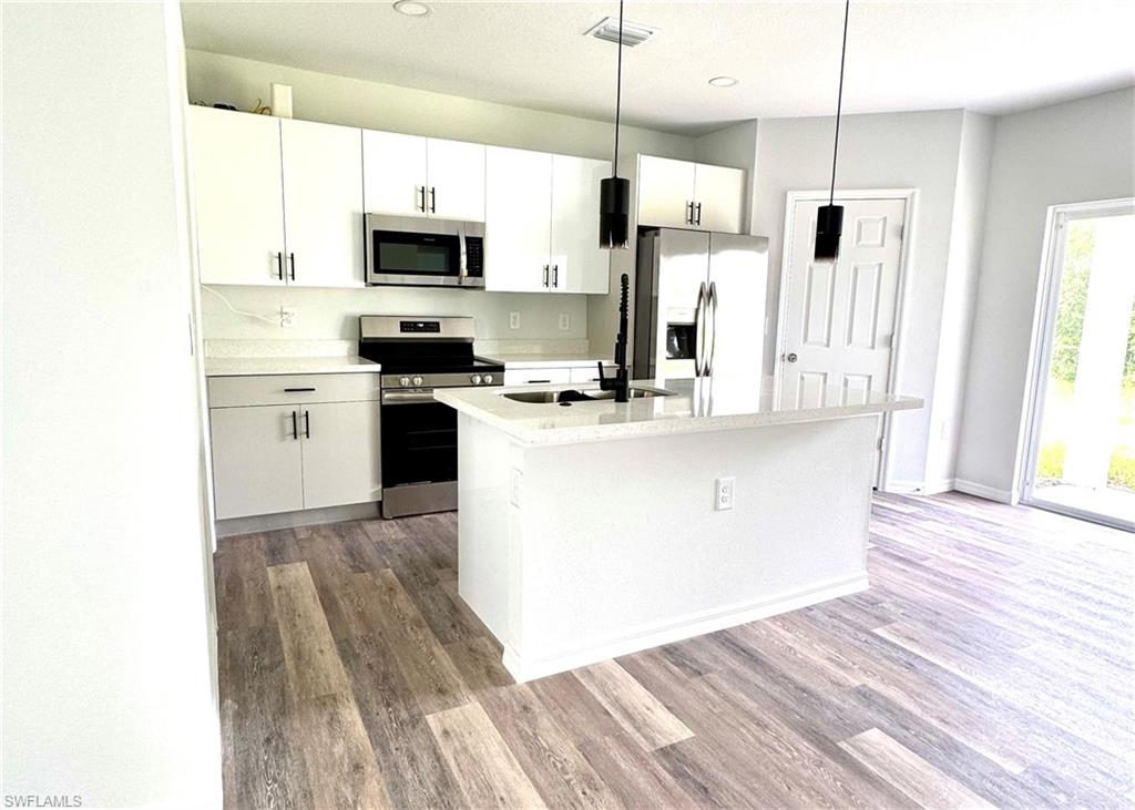 Kitchen featuring appliances with stainless steel finishes, white cabinets, decorative light fixtures, and recessed lighting