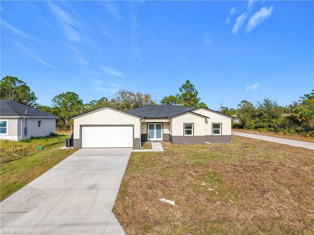 Ranch-style house featuring concrete driveway, a front lawn, a garage, and stucco siding