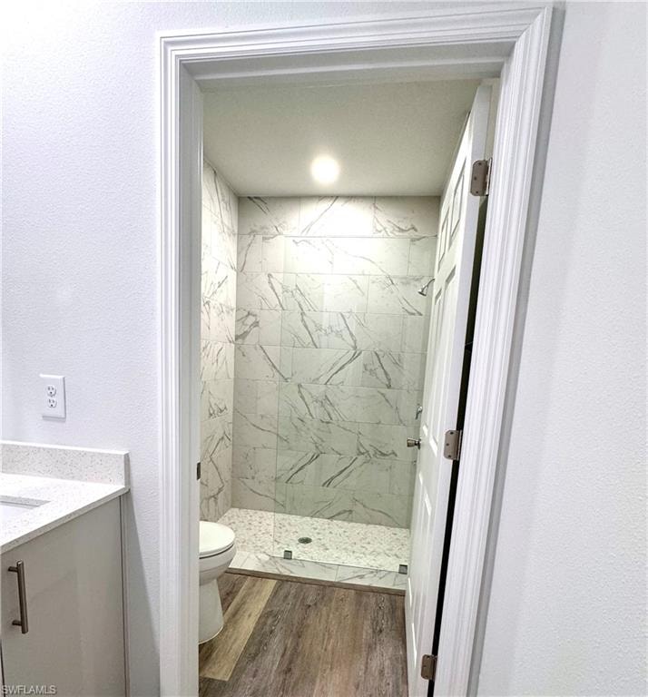 Full bathroom with vanity, a marble finish shower, wood finished floors, and a textured wall