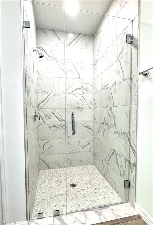 Full bath with a marble finish shower and marble look tile flooring